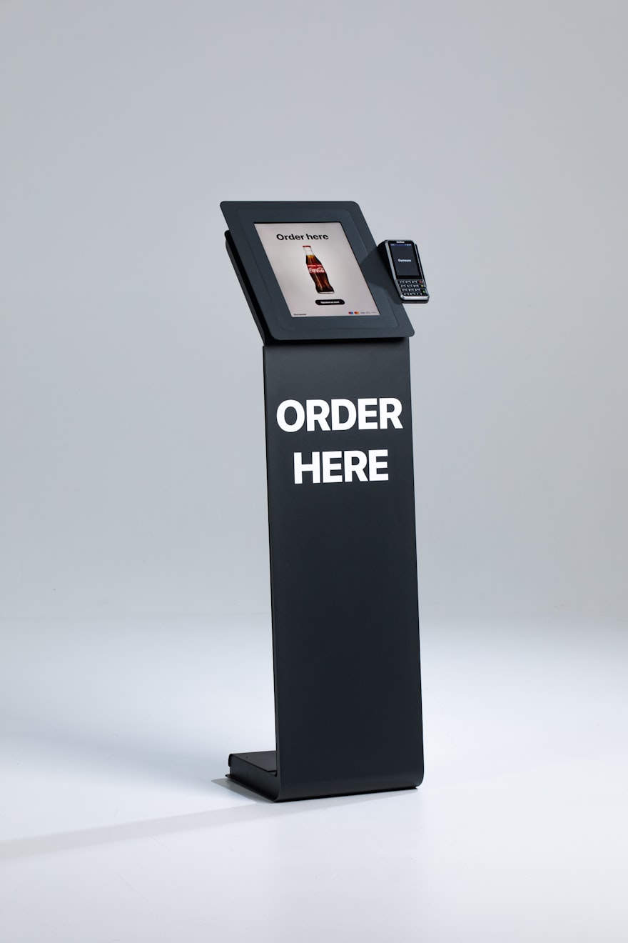 Self-order kiosk stand with a touchscreen ordering menu and a contactless card payment terminal